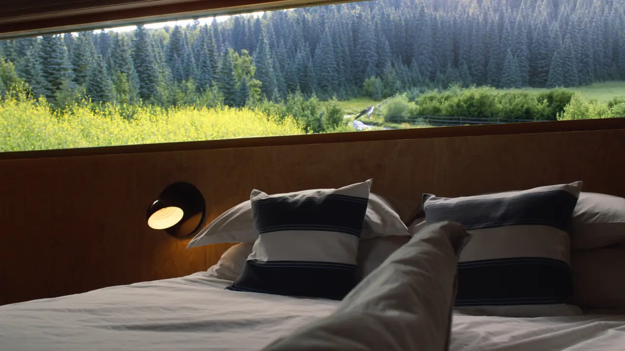 Frisch bezogenes Bett im Tiny House mit Blick in den Wald